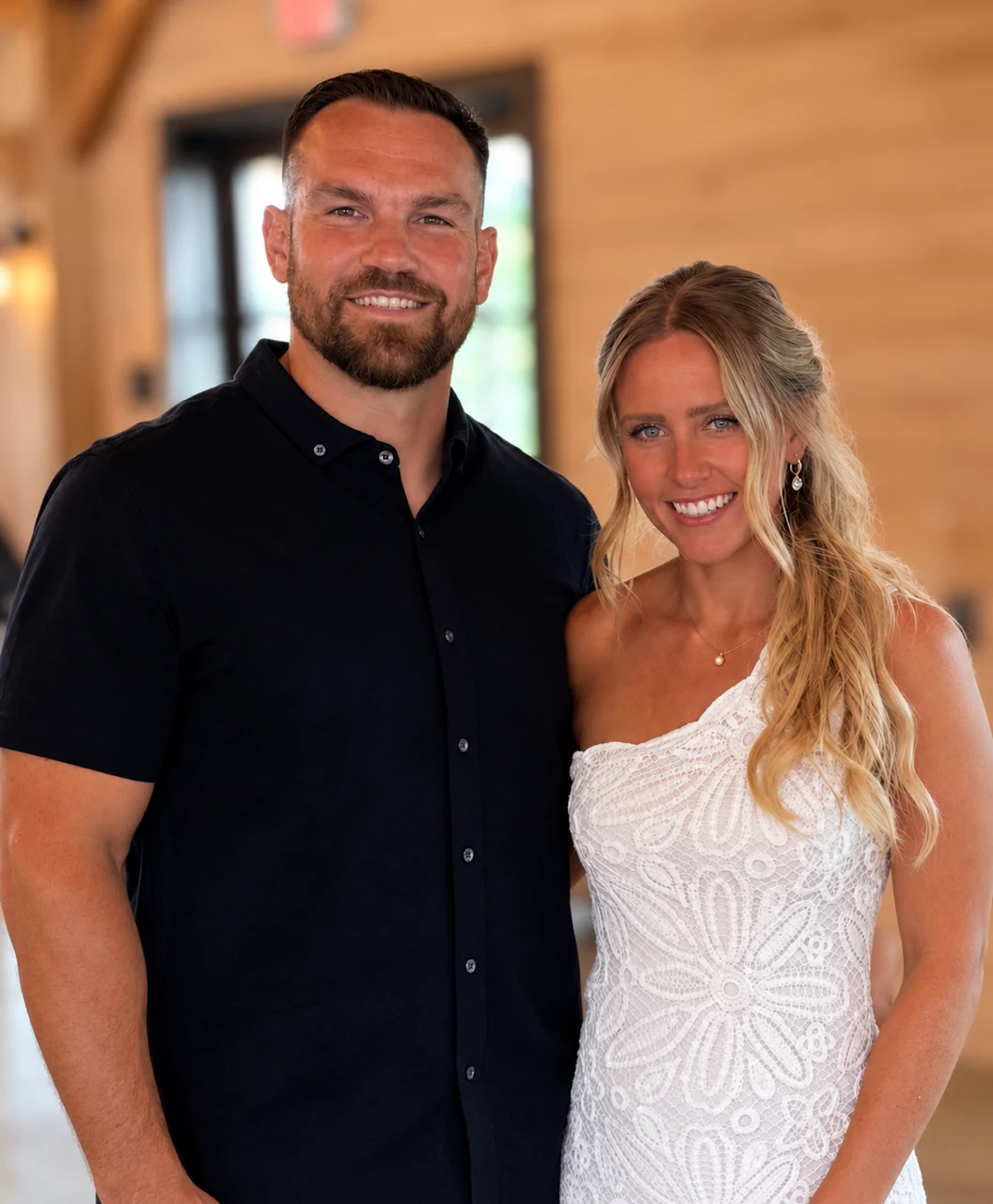 Bill on the left and Kara on the right, co-hosts of Sky Mountain Retreat, standing together in a warmly lit timber space