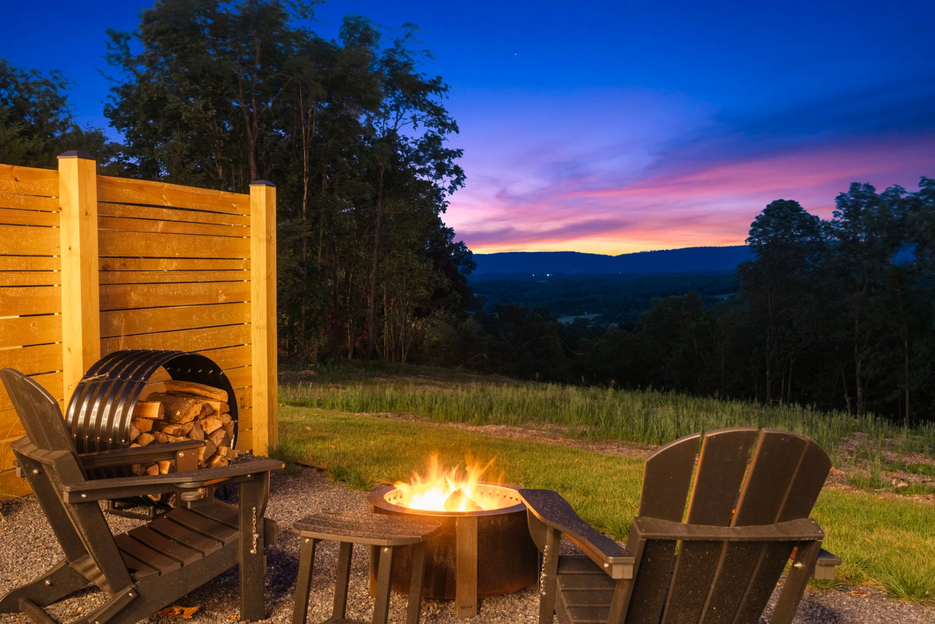 Fire pit glowing at dusk with mountain ridges beyond