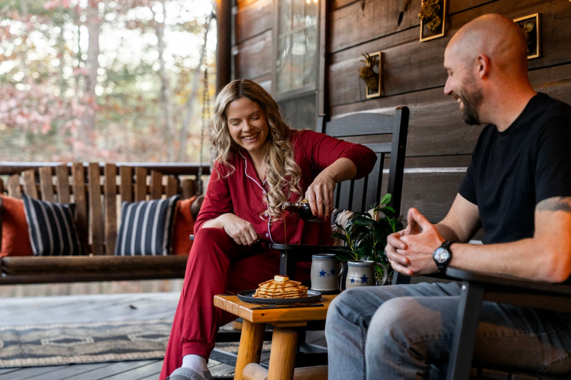 A couple sharing breakfast on a wood porch with the forest beyond